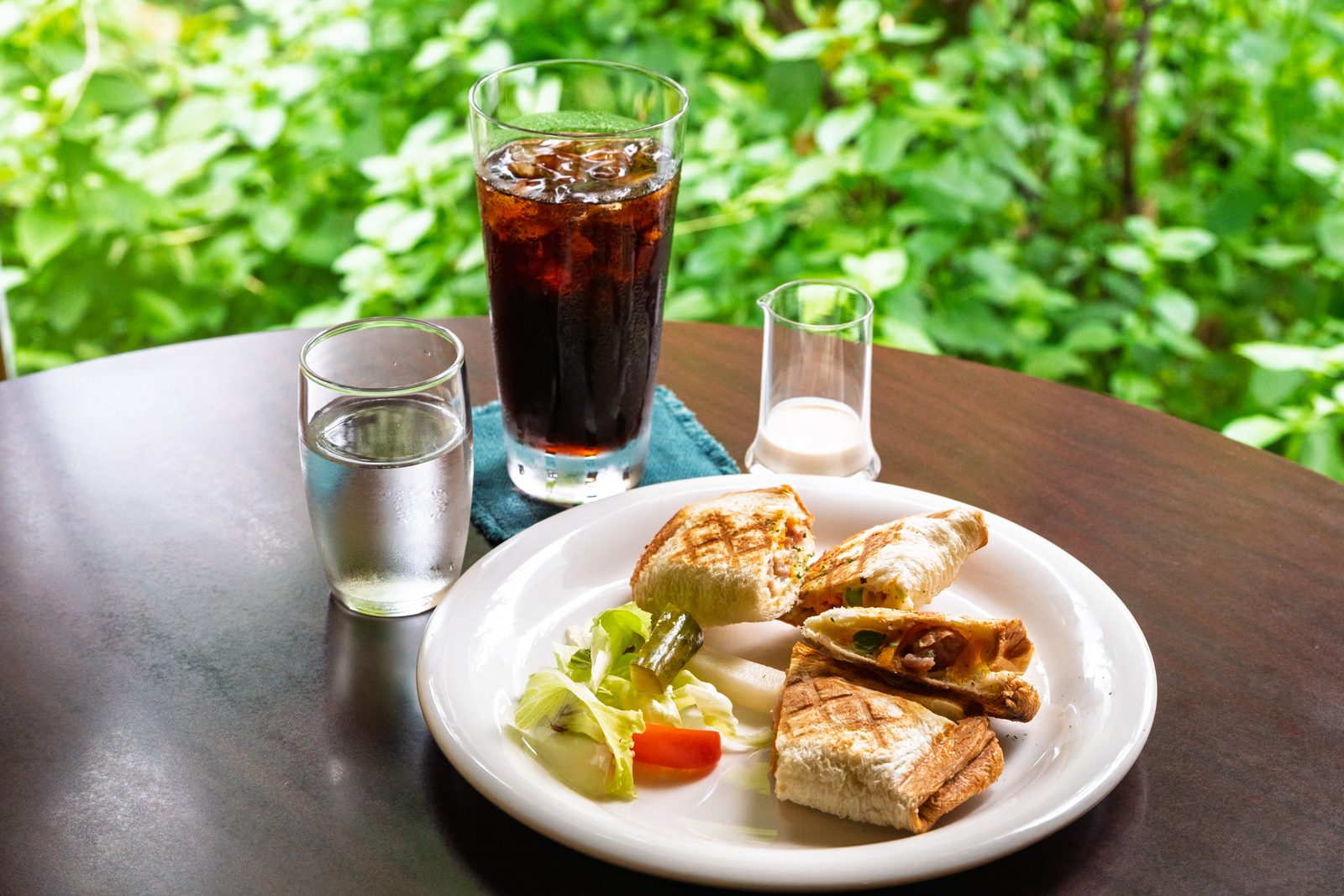 เมนูของว่างและกาแฟเย็นของร้านกาแฟ Otsukaya เสิร์ฟริมหน้าต่างที่มองเห็นสวน